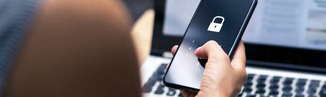 Female holding phone with security lock  in front of computer screen
