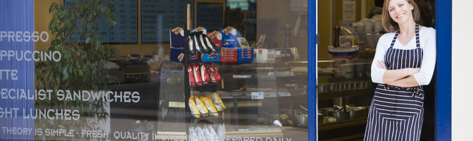 Female business owner, shop worker, standing in front of restaurant storefront. 