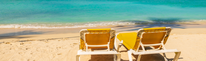 Tropical beach landscape with yellow sunbeds on the beach.