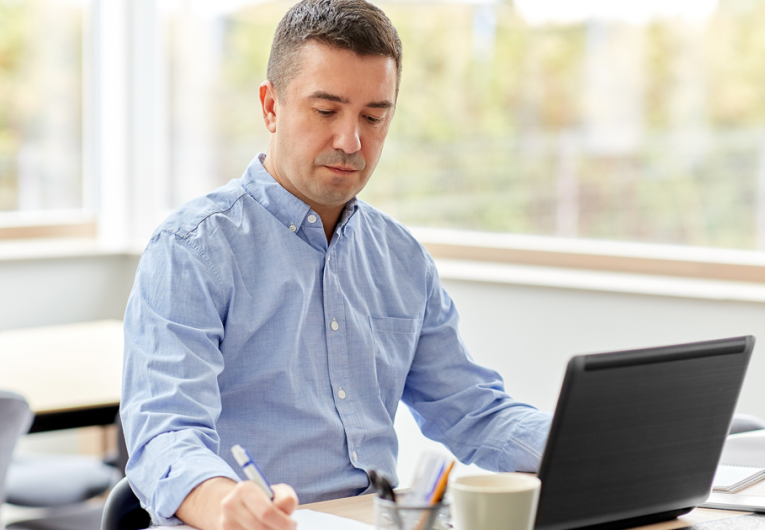 middle-aged man with calculator, papers and laptop computer working in office