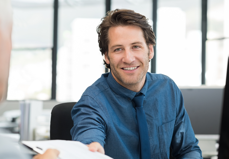 Close up of young businessman giving writing pad to senior businessman.