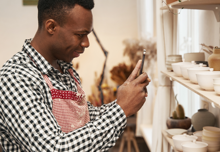 Male ceramist taking photos of earthenware products for sale