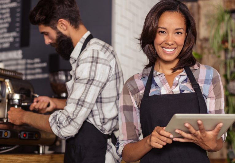Waitress using a tablet computer and waiter with coffee machine in the bar