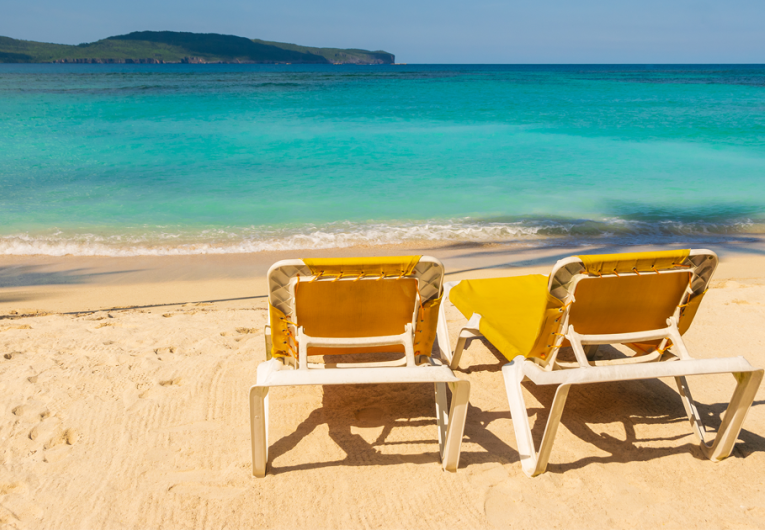 Tropical beach landscape with yellow sunbeds on the beach.