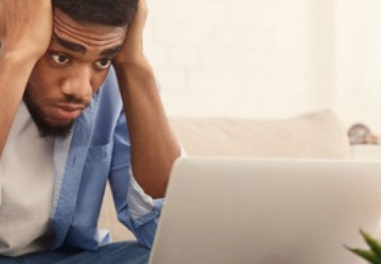 Man holding head in his hands while viewing laptop