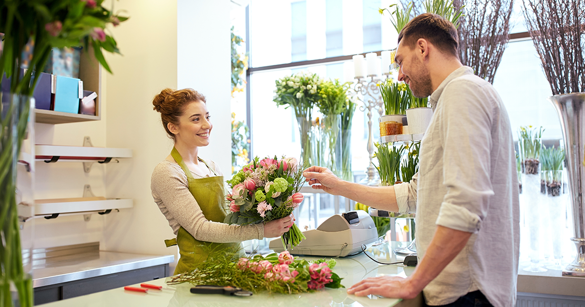 happy smiling florist woman making bouquet for and male customer at flower shop