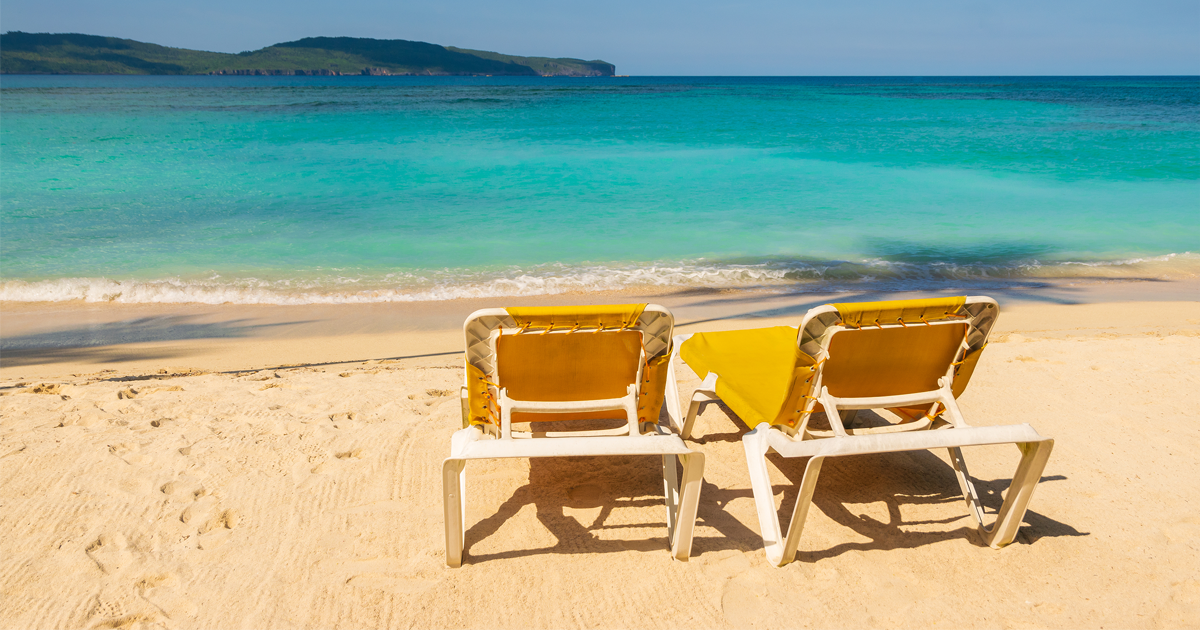 Tropical beach landscape with yellow sunbeds on the beach.